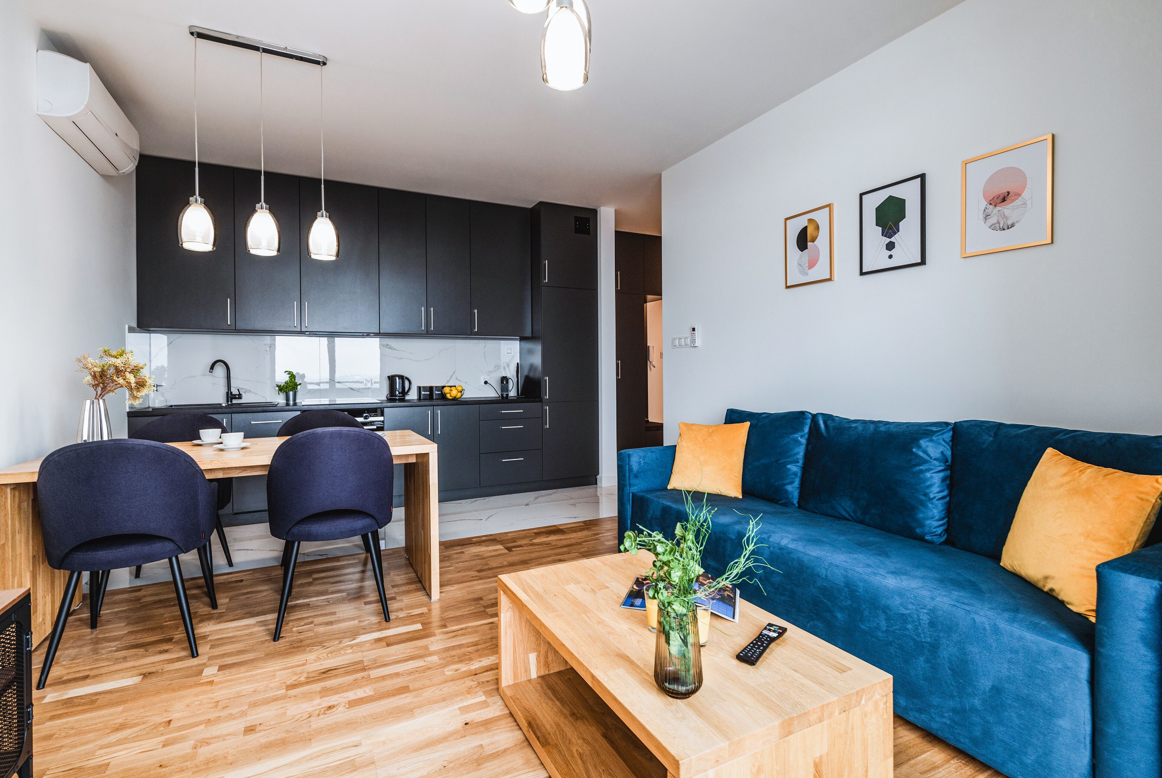 Un soggiorno moderno con un divano blu, un tavolino in legno e un'area pranzo con sedie e tavolo.