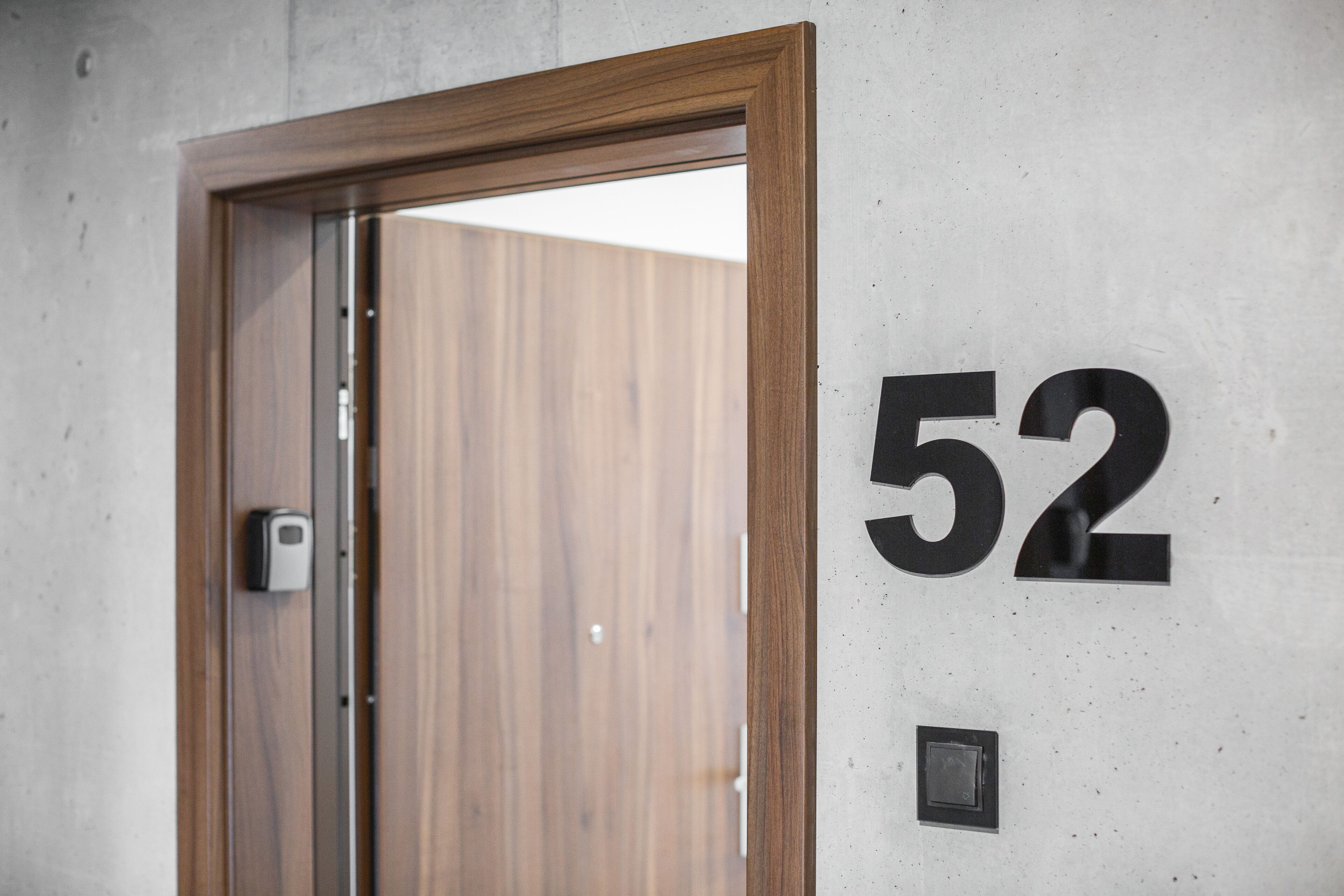 Una porta con stipite in legno e il numero 52 sulla parete.