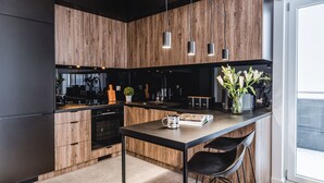 Een moderne keuken met houten kasten, een centraal eiland met barstoelen en hangende verlichting.