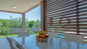A dining area with a table, wicker chairs, and a fruit basket.