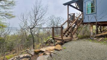 A wooden staircase leading to a house with a view of a body of water.