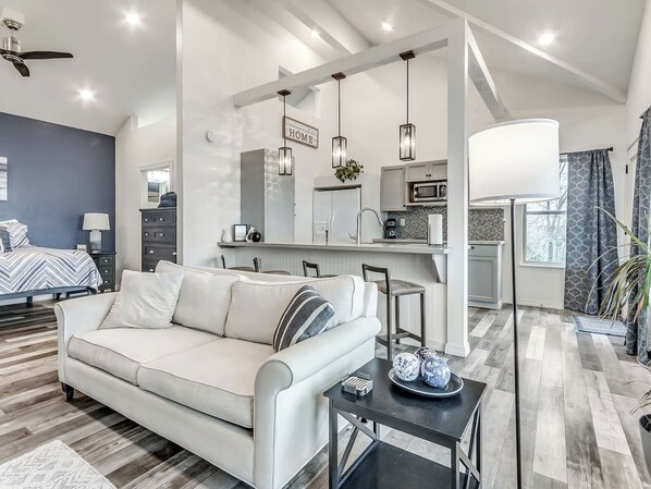 A modern living room with a sofa, a dining area, and a kitchen with a microwave.