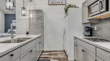 A modern kitchen with a stainless steel refrigerator, a microwave, and a coffee maker on the counter.