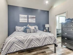 A bedroom with a bed, a dresser, and two wall-mounted paintings.
