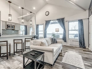 A modern living room with a sofa, coffee table, and bar stools.