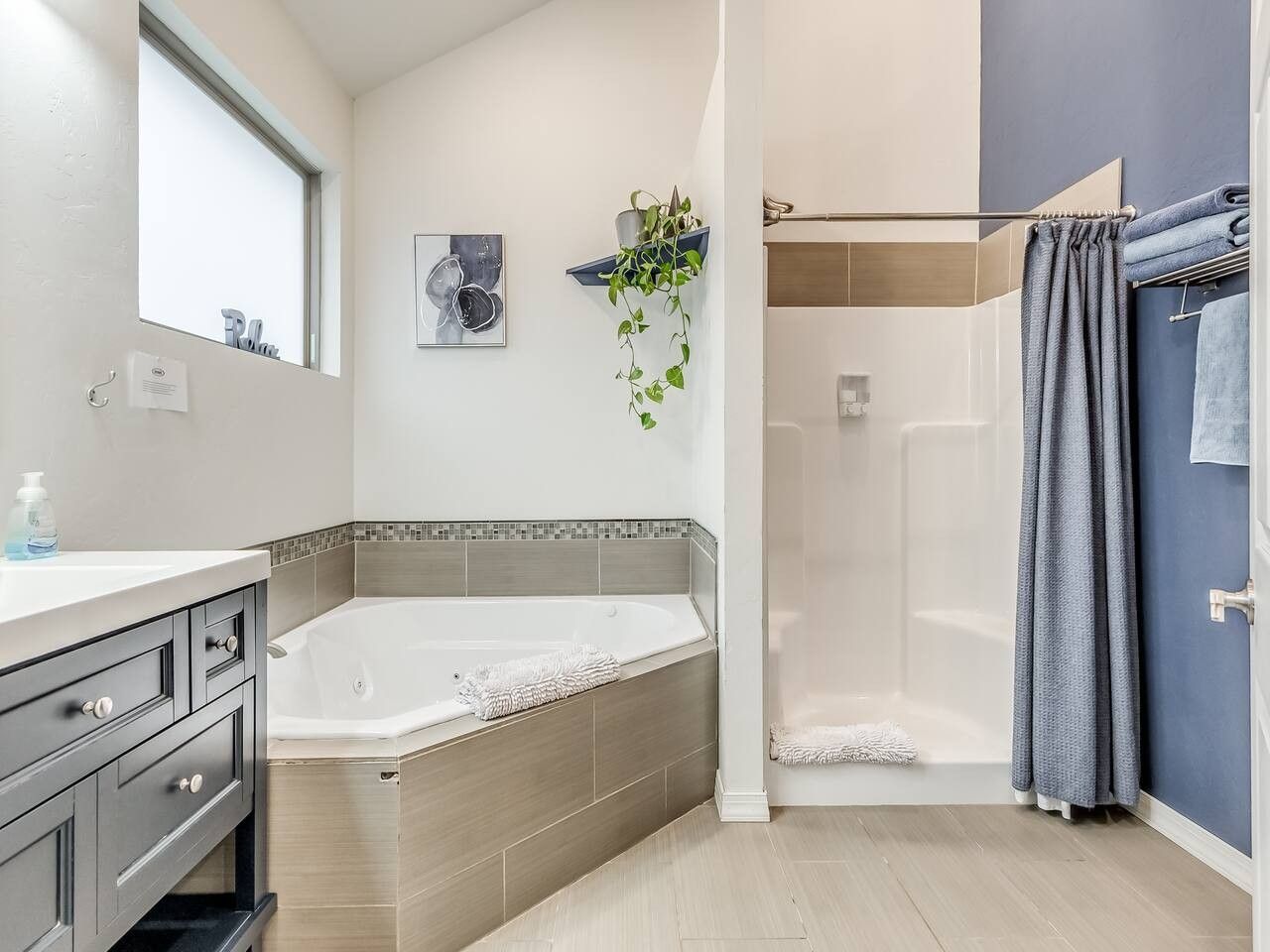 Un baño moderno con bañera, ducha y tocador con cajones.