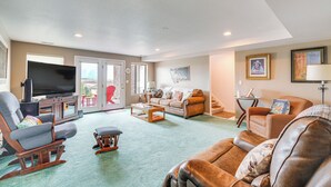 A living room with a television, sofas, a coffee table, and a fireplace. - Inviting Great Falls Home w/ Wraparound Deck! (Great Falls)