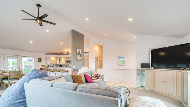 A spacious living area with a large gray sectional sofa, a flat-screen TV, and a ceiling fan. - Inviting Great Falls Home w/ Wraparound Deck! (Great Falls)