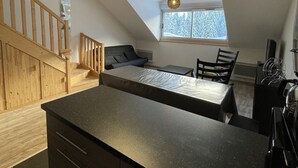 Une cuisine moderne dotée d’un îlot central, d’un escalier en bois et d’un plafond en pente avec une lucarne.
