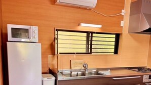 A compact kitchen with a refrigerator, microwave, sink, and a window with blinds. - AZ Hotel Inn Amamimanya (Amami)