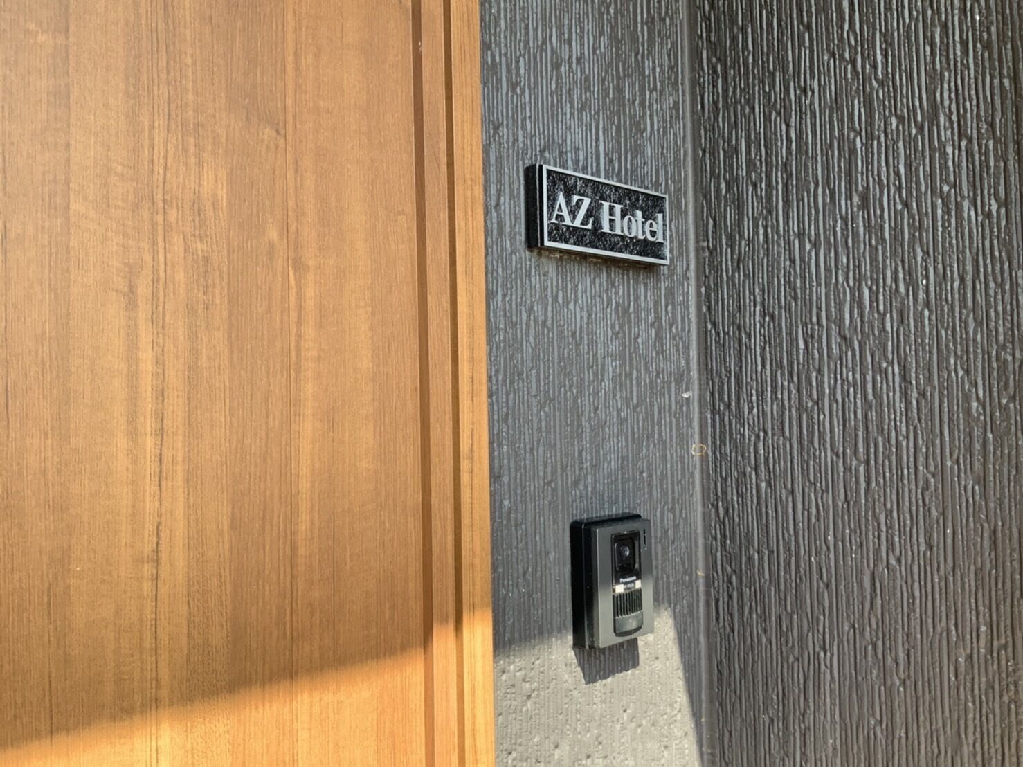 Eine Holztür und eine strukturierte Wand mit einem Schild, auf dem "AZ Hotel" steht.