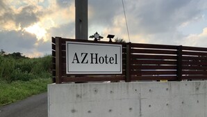 A sign for AZHotel with a wooden fence and a concrete wall. - AZ Hotel Inn Amamimanya (Amami)
