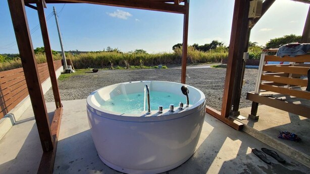 A hot tub in a covered outdoor area with a wooden bench and a concrete floor. - AZ Hotel Inn Amamimanya (Amami)