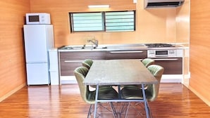 A compact kitchen with a dining table, a refrigerator, a microwave, and a stove. - AZ Hotel Inn Amamimanya (Amami)