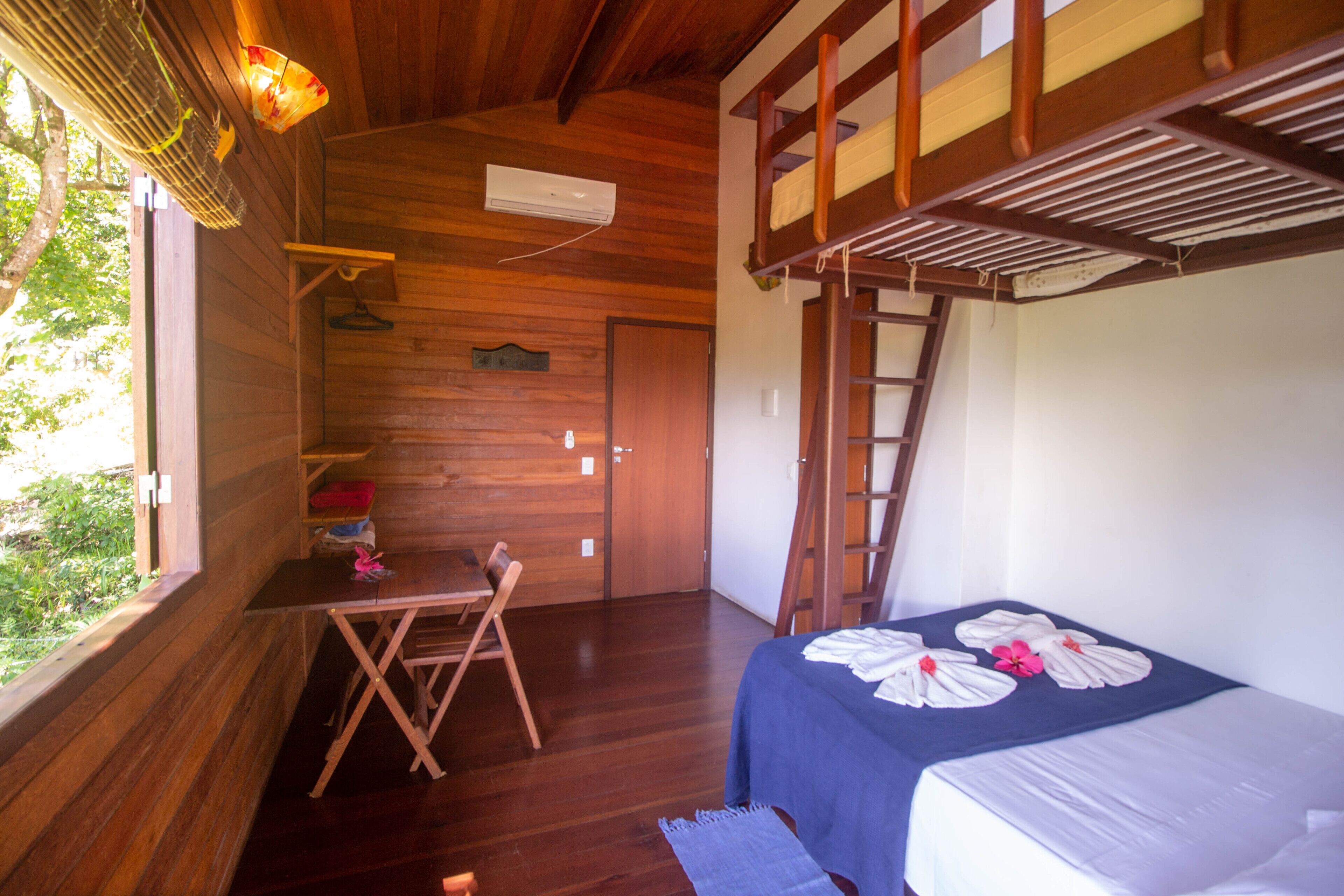 Una camera in una casetta di legno con un letto a castello, una scrivania e una sedia.