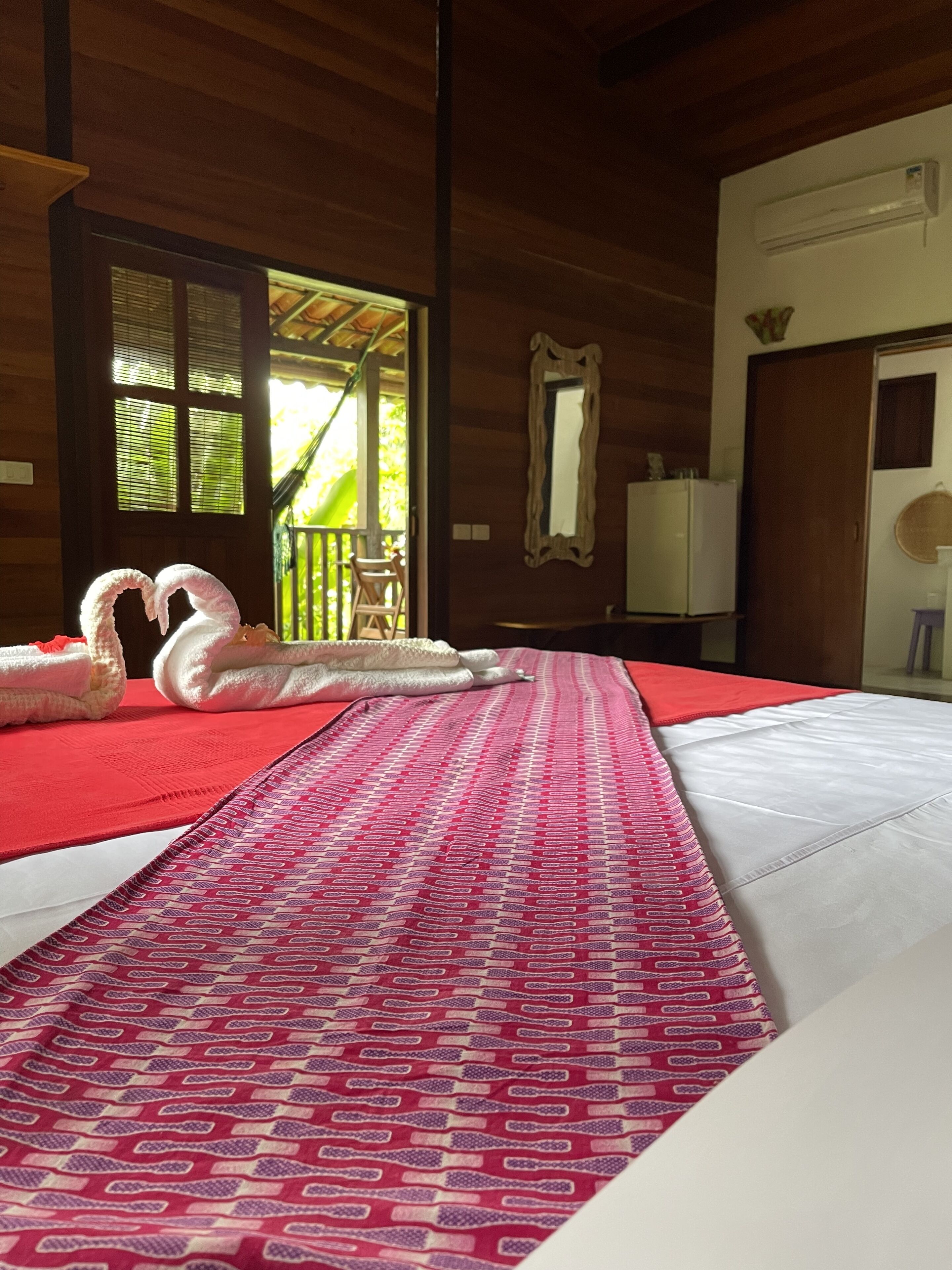 Una habitación de hotel con cama, techo de madera, ventana y puerta.