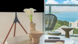 A modern room with a view of the sea, a tripod, a vase with white flowers, a book titled 'A Tree in the House', and a chair. - Penthouse W/Bayviews! 2 Bdrm Condo In Miami Design (Miami)