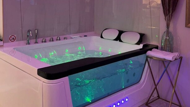 A modern spa room with a large bathtub, a glass-enclosed shower area, and ambient lighting. - Superb sauna jacuzzi apartment Luxury&Spa (Herblay)