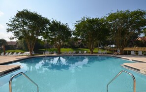 Relax by the serene pool surrounded by lush greenery and lounge chairs.