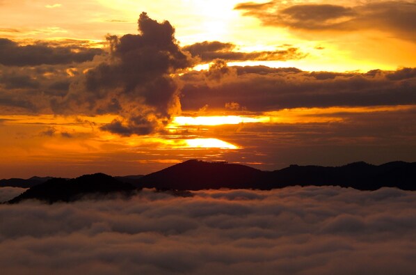 Eine Bergsilhouette mit Sonnenuntergang und Wolken am Himmel.