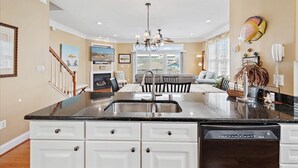 A spacious kitchen with a central island, white cabinetry, and a dishwasher.