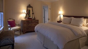 Un dormitorio con una cama grande, un aparador, una silla y dos lámparas de noche.