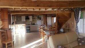 Una cocina rústica con vigas de madera, un comedor con sillas y un sofá en un espacio de estar acogedor.