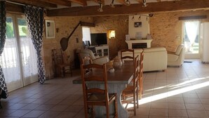 Un interior rústico con pared de piedra, muebles de madera, chimenea y televisor.