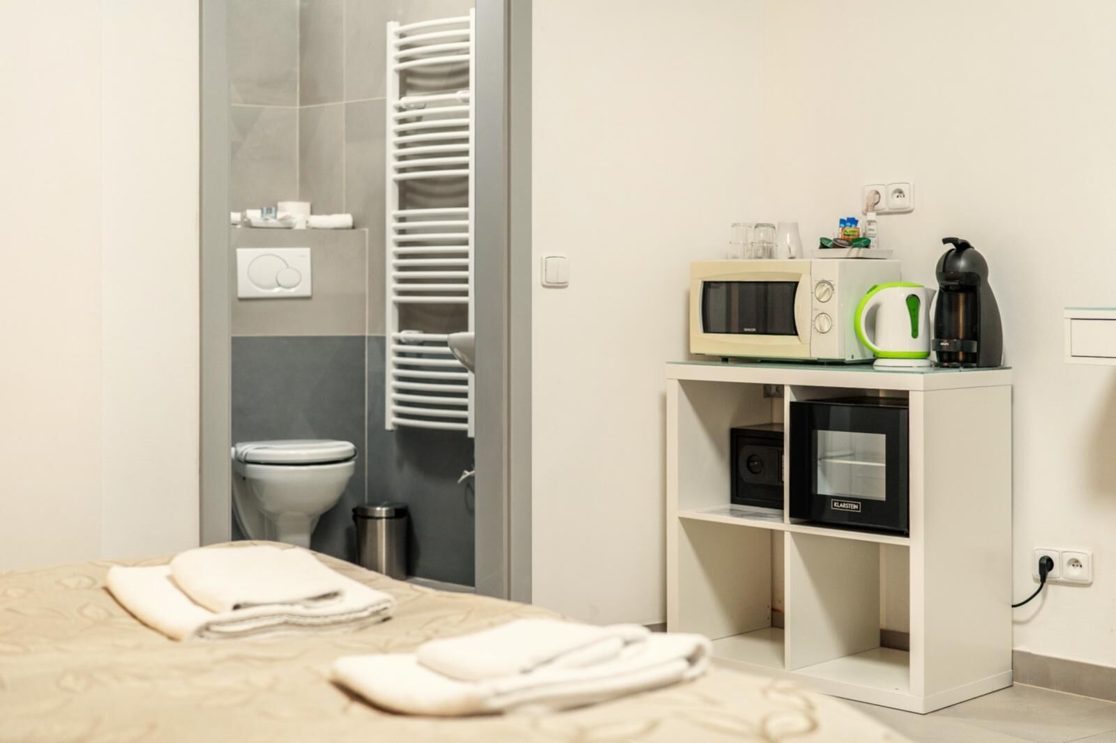 Een hotelkamer met een bed, een magnetron, een waterkoker en een kleine koelkast.