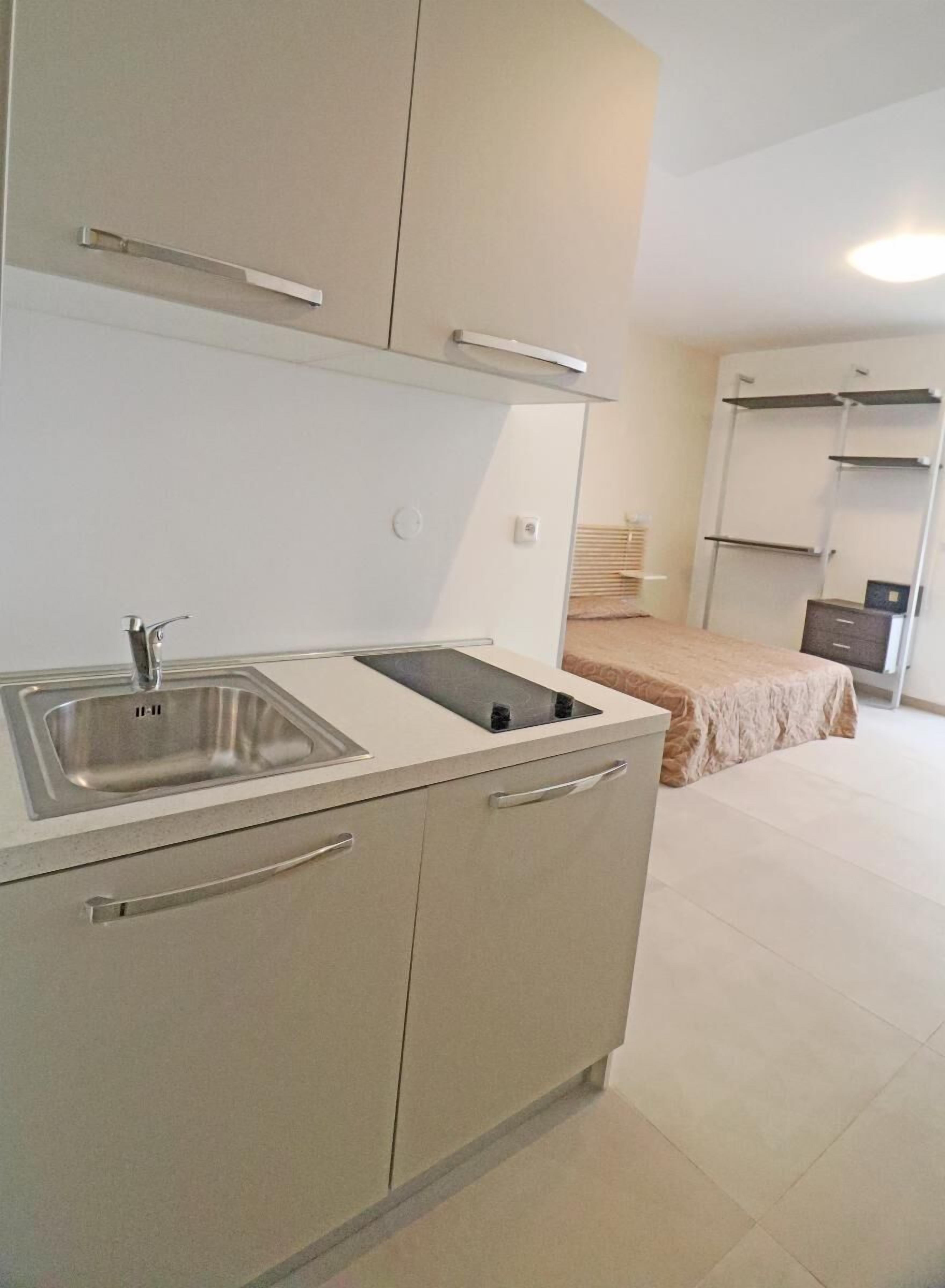 A compact kitchen with a sink, stove, and cabinets.
