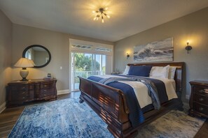 A bedroom with a large bed, a dresser, a mirror, and a painting on the wall. - Point Break at Agate Beach, Sleeps 12, Oceanfront, Loft, Game Room, Hot Tub, Beach Access, BBQ (Newport)