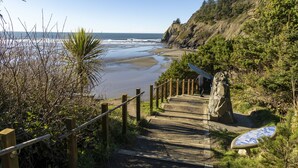 A coastal path leading to a beach with a wooden staircase and a large rock. - Point Break at Agate Beach, Sleeps 12, Oceanfront, Loft, Game Room, Hot Tub, Beach Access, BBQ (Newport)