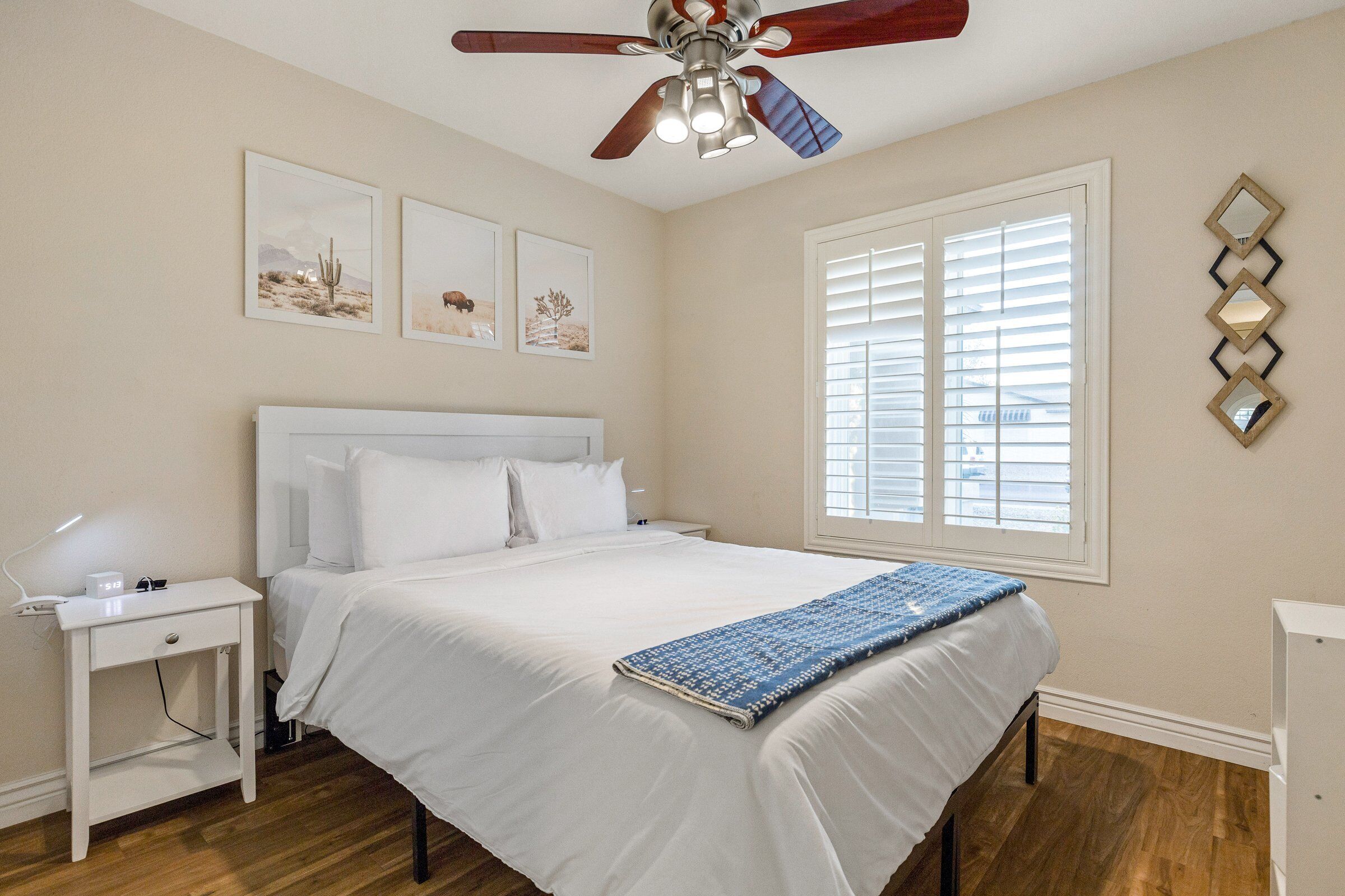 A bedroom with a bed, bedside table, and a ceiling fan.