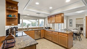 A spacious kitchen with granite countertops, wooden cabinets, and a central island.