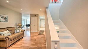 A modern interior with a wooden floor, a leather sofa, a staircase, and a painting of a bird. - Sunny Marco Island Gem w/ Shared Pool & Dock! (Marco Island)