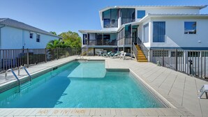 A swimming pool with a 'NO DIVING' sign, a covered deck area, and a multi-story building with balconies. - Sunny Marco Island Gem w/ Shared Pool & Dock! (Marco Island)