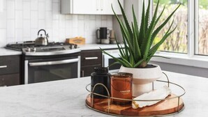 Una cucina moderna con mobili bianchi, una cappa in acciaio inossidabile e un'ampia finestra con vista sul verde.