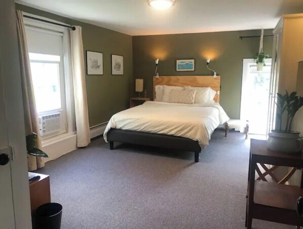 Une chambre à coucher avec un lit, des tables de chevet, une fenêtre avec des rideaux et des lampes fixées au mur.