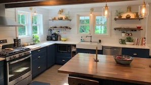 Una cocina moderna con armarios azul oscuro, una isla de madera e iluminación colgante.
