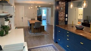 Una cocina moderna con una isla de madera, armarios empotrados e iluminación colgante.