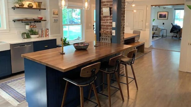 Una cocina moderna con una isla central, taburetes de bar e iluminación colgante.