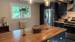 Una cocina moderna con una isla de madera, electrodomésticos de acero inoxidable e iluminación colgante.