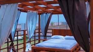 A wooden bed with a canopy, a small table, and a view of the outdoors. - Impeccable 3-bed House in Prampram Accra (Prampram)