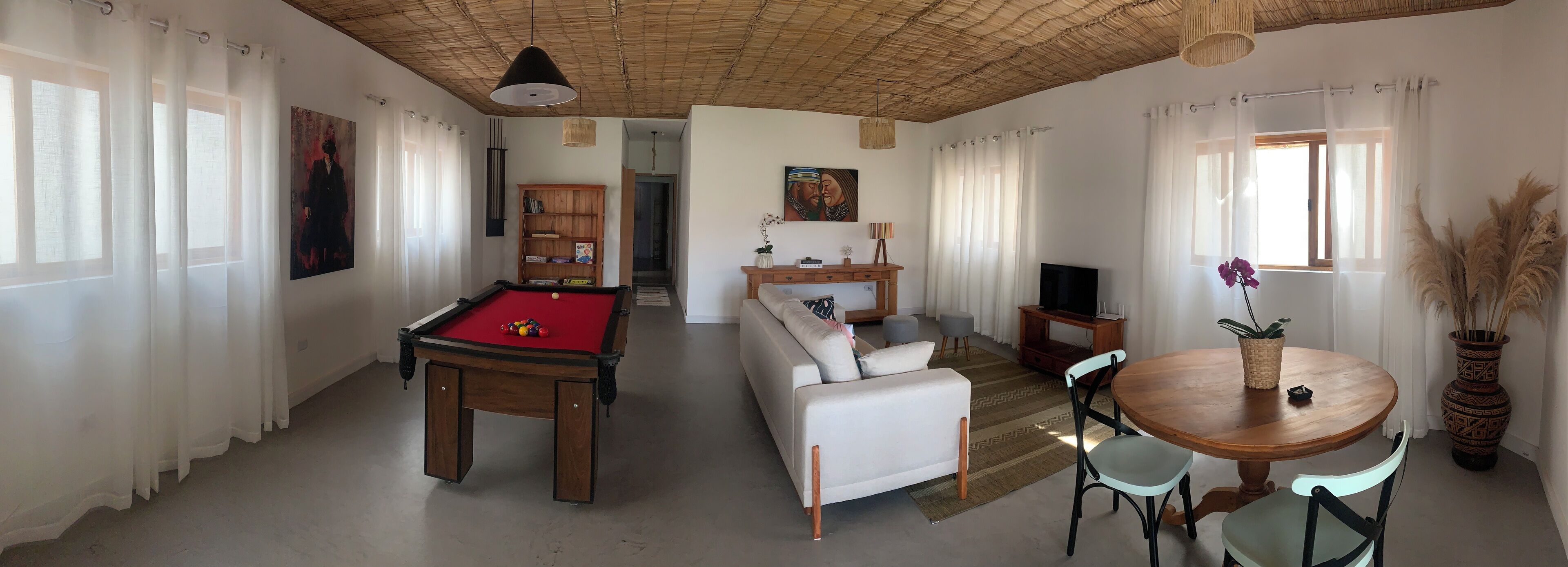 Una sala de estar con mesa de billar, sofá, mesa de comedor y televisor.