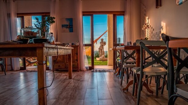 Een gezellig restaurant met houten vloeren, een centrale tafel met stoelen, en een standbeeld op de achtergrond.
