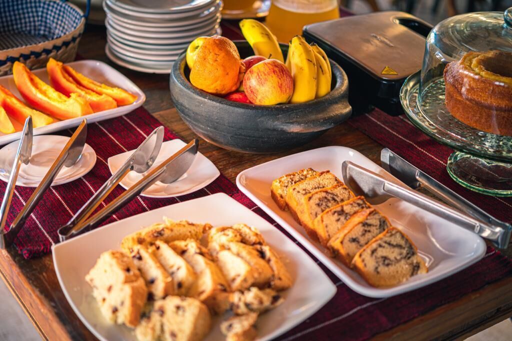 A breakfast buffet with sliced fruits, pastries, and a cake on a wooden table.