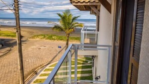Een balkon met uitzicht op het strand, een palmpende en een betegelde vloer.