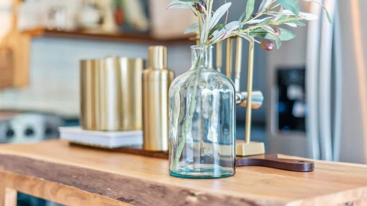 A clear glass vase with a plant on a wooden surface.
