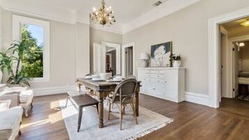 Um quarto amplo com uma mesa de jantar de madeira, armários brancos e um candelabro.