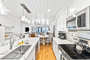 Une cuisine moderne avec des meubles blancs, des appareils en acier inoxydable et un plancher en bois.